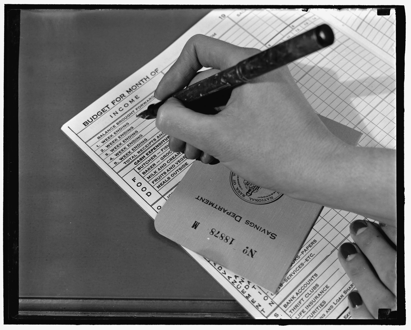 A worn budget book and bank book open on a desk, pages filled with handwritten figures